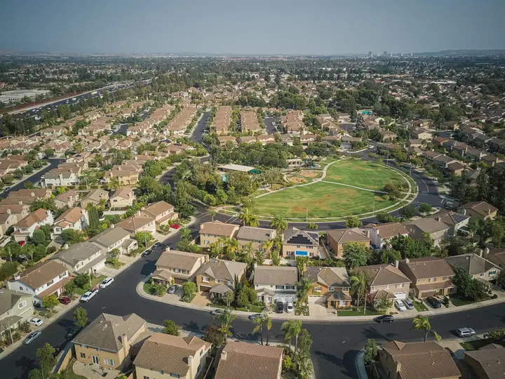 Wide aerial view of a neighborhood of tiled roofs around a park