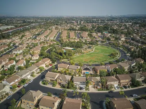 Wide aerial view of a neighborhood of tiled roofs around a park
