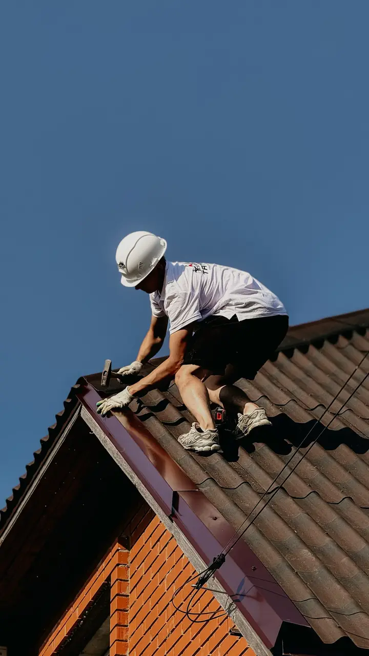 Roofer in a safety helmet working along a roof edge
