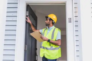 Inspector in a hard hat checking a door frame