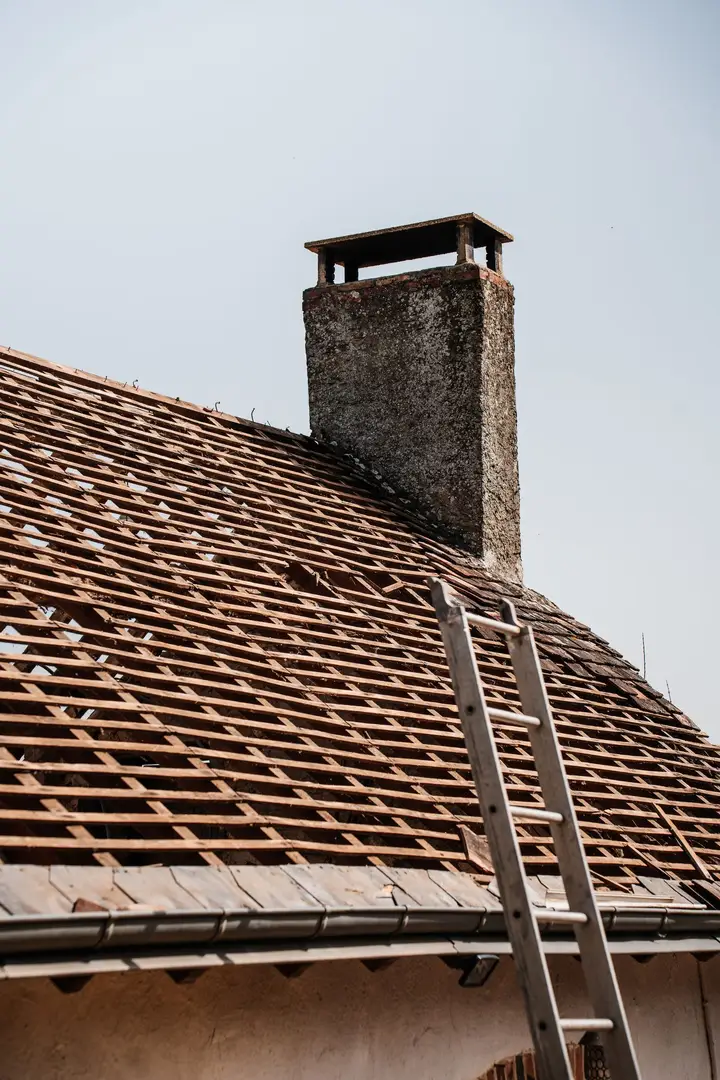 Roof stripped down to its battens beside a chimney