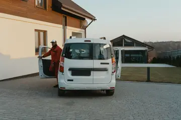 Worker stepping out of a white van in a driveway