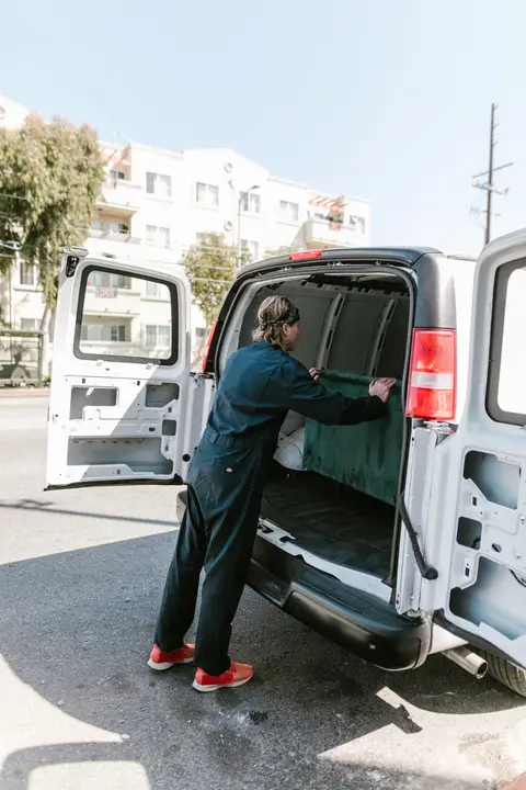 Worker in coveralls loading a work van